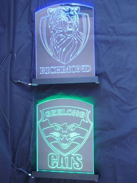 Two glowing acrylic plaques: blue Richmond Tigers logo above, green Berwick Cats logo below. — Advanced Poly in Darwin, NT