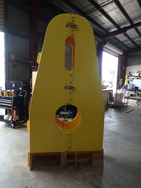 Yellow industrial machine standing in a warehouse, with a round opening and vertical gauge. — Advanced Poly in Darwin, NT
