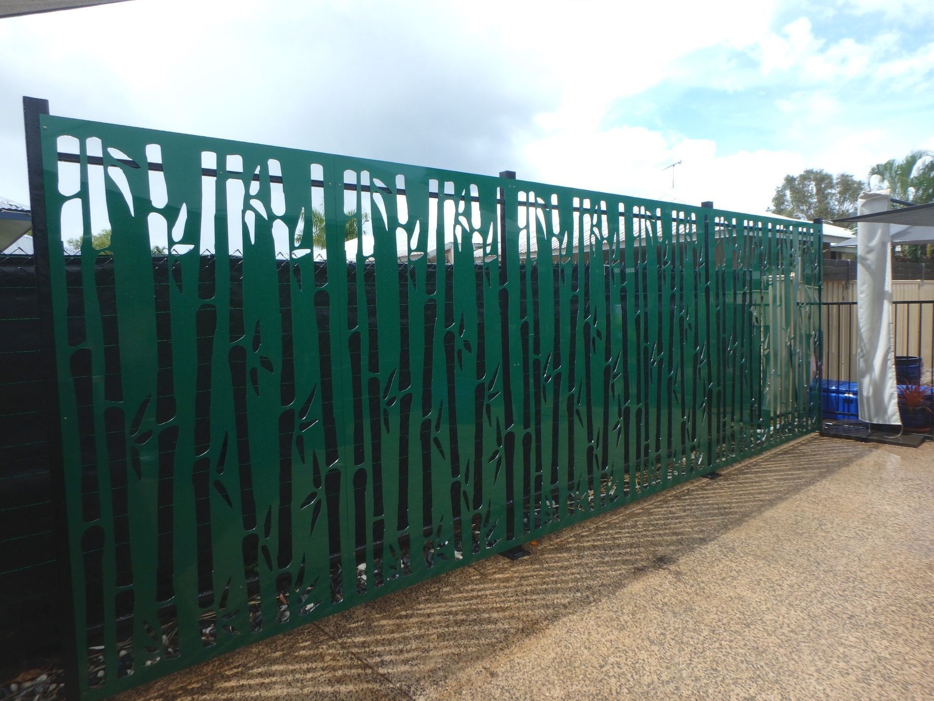 Green metal fence beside a gravel path under a cloudy sky — Advanced Poly in Darwin, NT