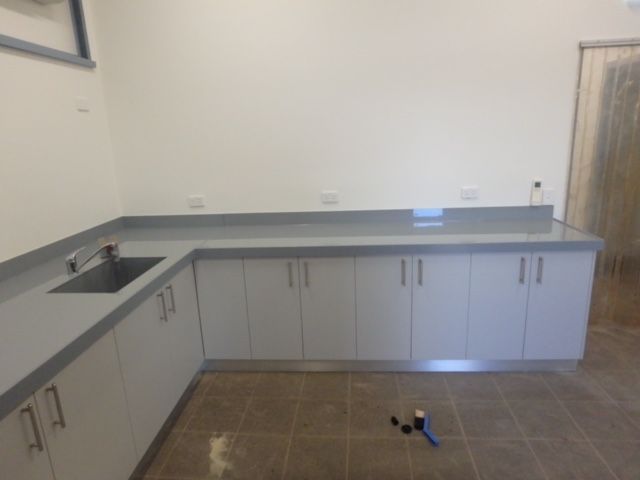 Empty modern kitchen with gray cabinets, black countertop, and brown tile floor — Advanced Poly in Darwin, NT 