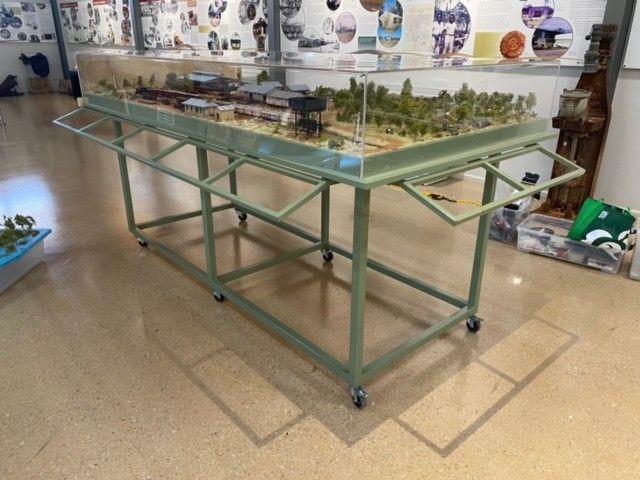 Glass display table with a detailed miniature model landscape in a museum or exhibit space — Advanced Poly in Darwin, NT
