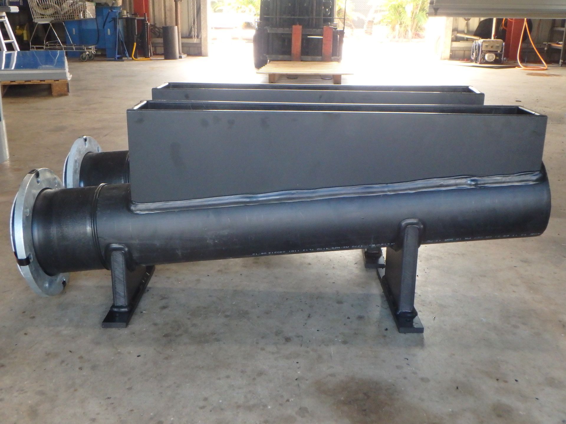 Large black industrial machine component on a warehouse floor, supported by metal legs. — Advanced Poly in Darwin, NT