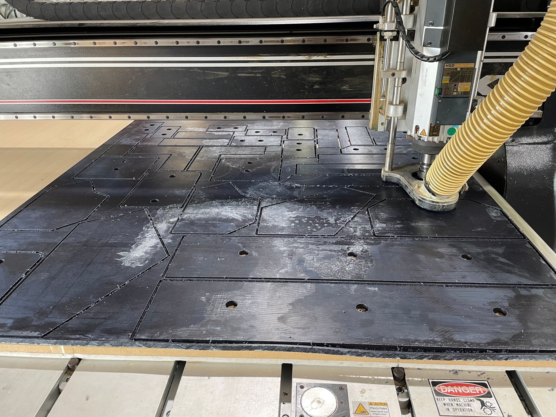 Black industrial machine bed with wet black panels and a yellow hose in a workshop — Advanced Poly in Darwin, NT