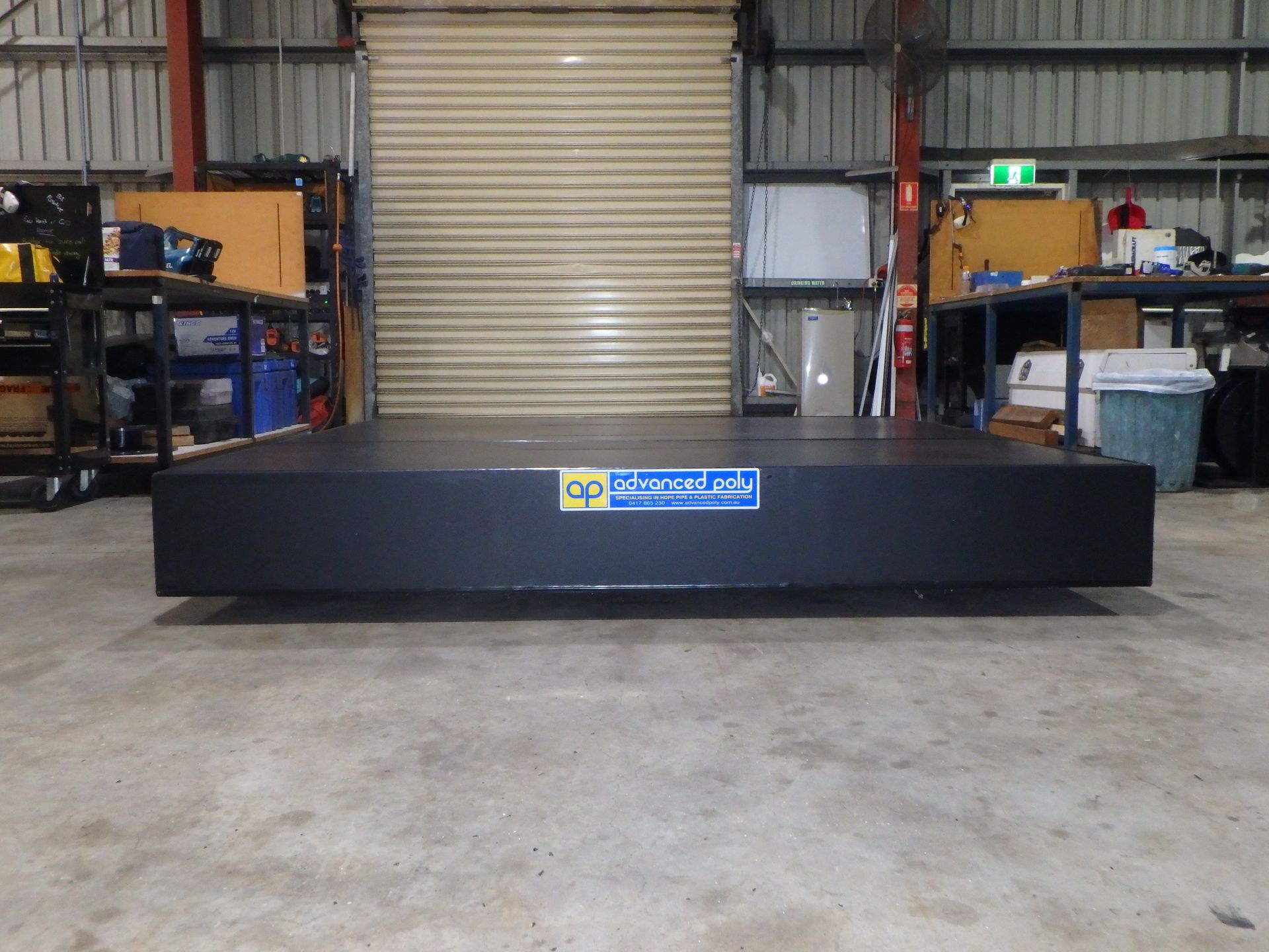 Black rectangular industrial unit in a warehouse, with a blue logo on the front. — Advanced Poly in Darwin, NT — Advanced Poly in Darwin, NT 