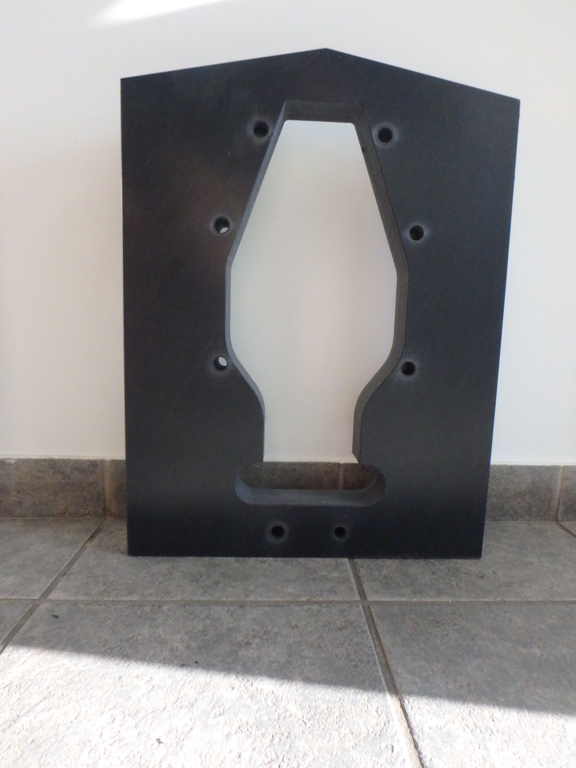 Black foam cutout panel with multiple holes, standing on a tiled floor against a wall. — Advanced Poly in Darwin, NT — Advanced Poly in Darwin, NT 