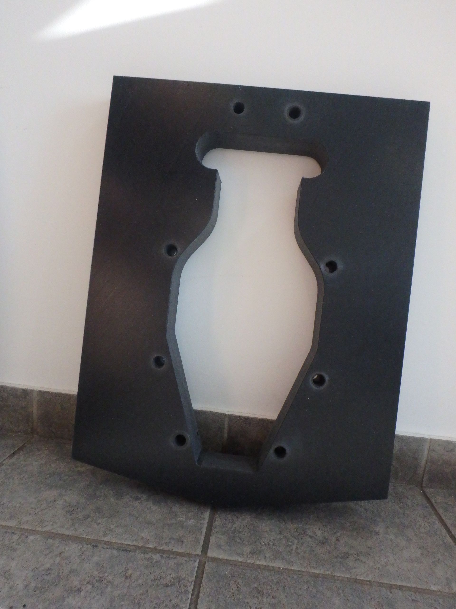 Black rectangular panel with a vase-shaped cutout and several mounting holes, leaning against a wall on tile floor — Advanced Poly in Darwin, NT — Advanced Poly in Darwin, NT 