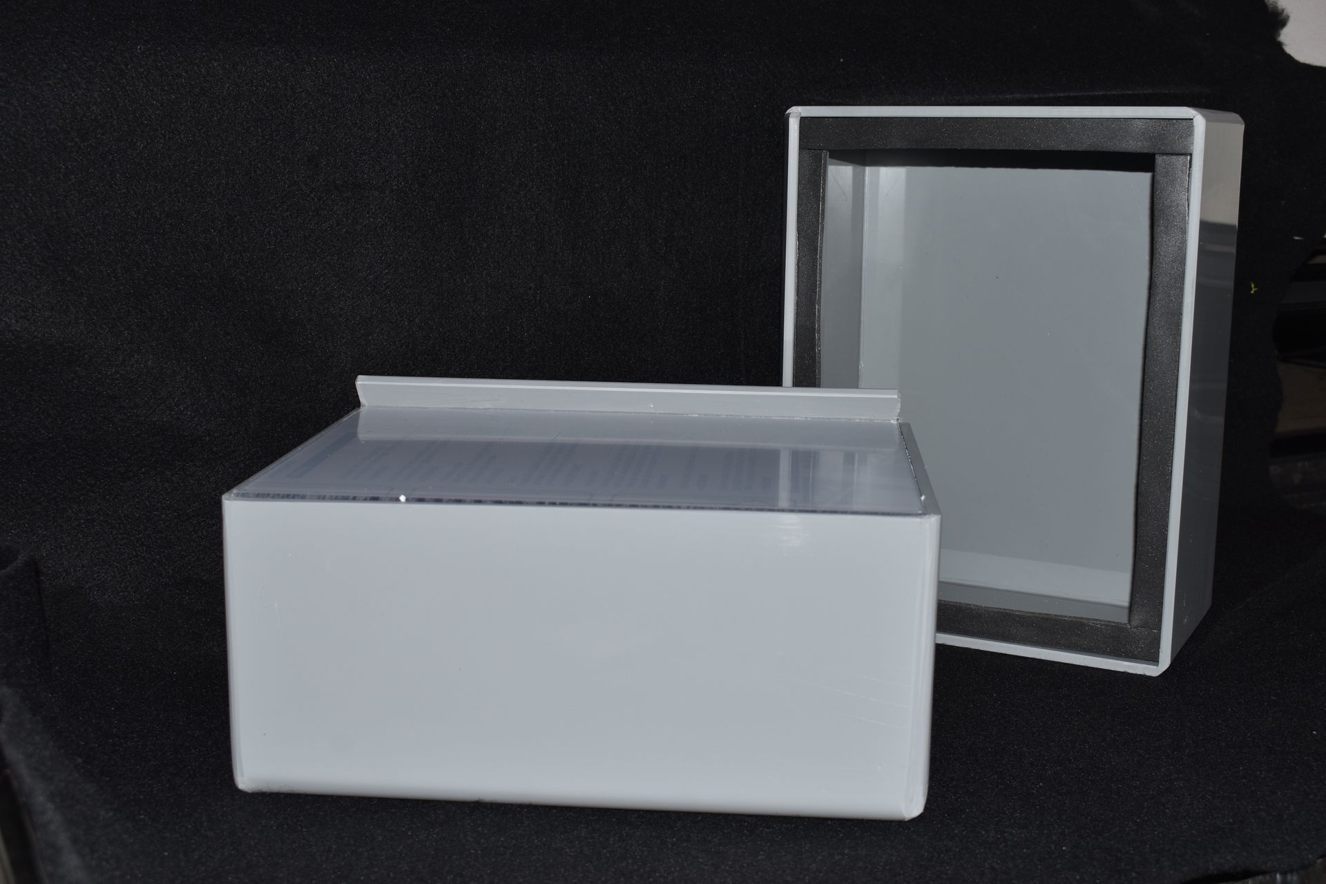 White rectangular box with a gray lid beside an open clear display case on a black background — Advanced Poly in Darwin, NT 
