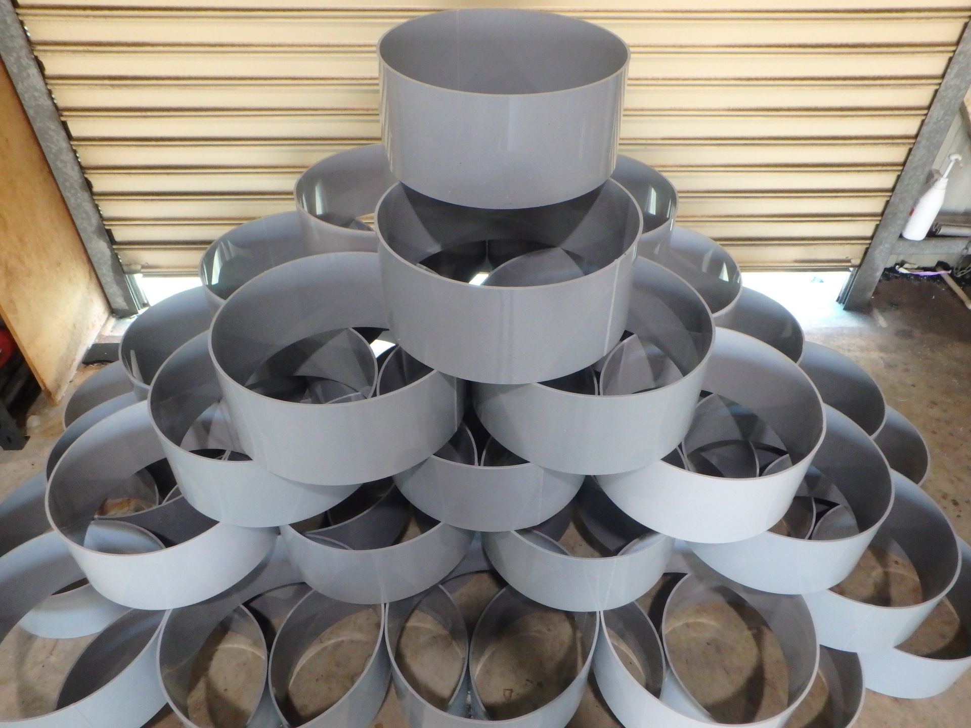Stacked gray metal rings arranged in a pyramid against a corrugated wall — Advanced Poly in Darwin, NT — Advanced Poly in Darwin, NT 