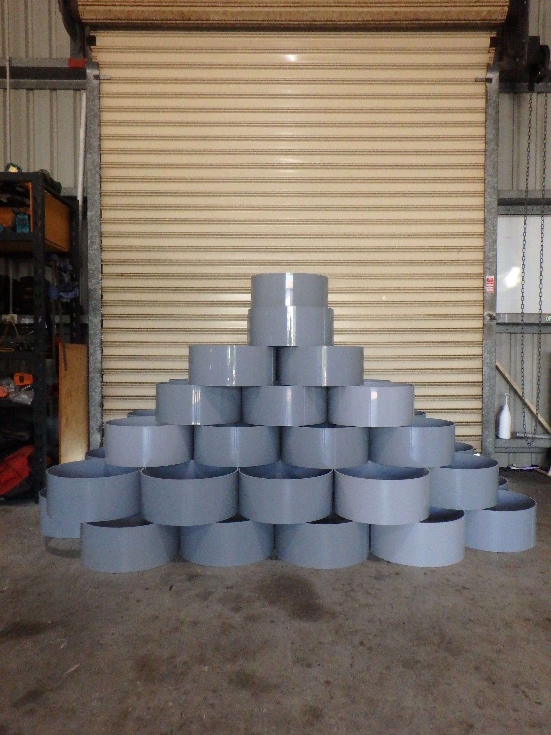 Stacked gray cylindrical containers in a pyramid inside a warehouse doorway — Advanced Poly in Darwin, NT — Advanced Poly in Darwin, NT 