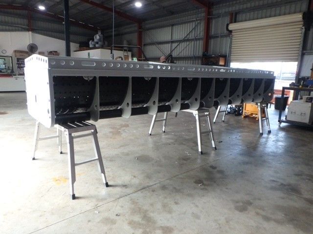 Long black industrial machine section on metal stands inside a warehouse workshop — Advanced Poly in Darwin, NT — Advanced Poly in Darwin, NT 