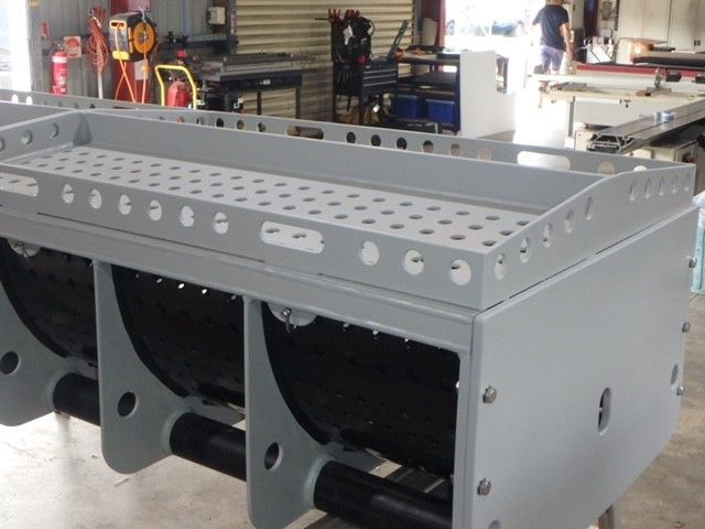 Gray metal industrial machine frame in a workshop, with large circular cutouts and bolted panels. — Advanced Poly in Darwin, NT — Advanced Poly in Darwin, NT 