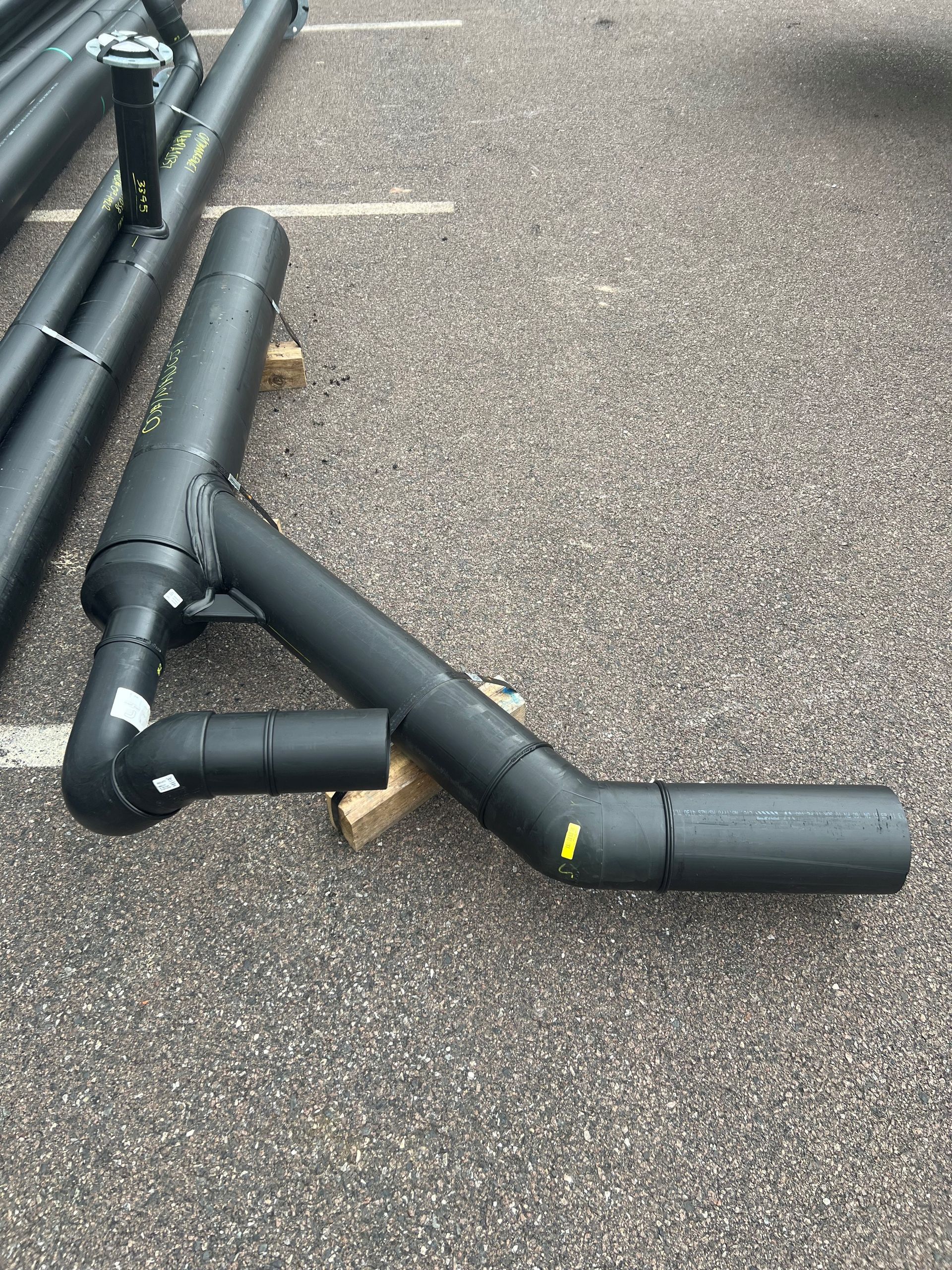 Black pipes and fittings laid out on a paved surface outdoors. — Advanced Poly in Darwin, NT