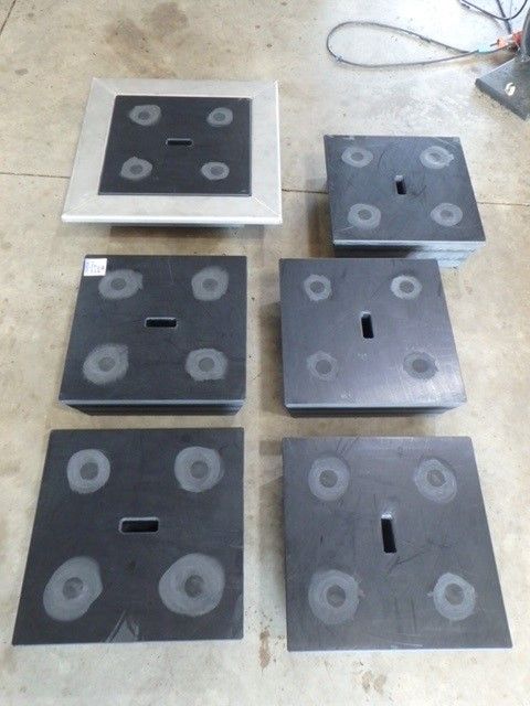 Six black square plates with circular markings, arranged on a concrete floor with wires nearby. — Advanced Poly in Darwin, NT — Advanced Poly in Darwin, NT