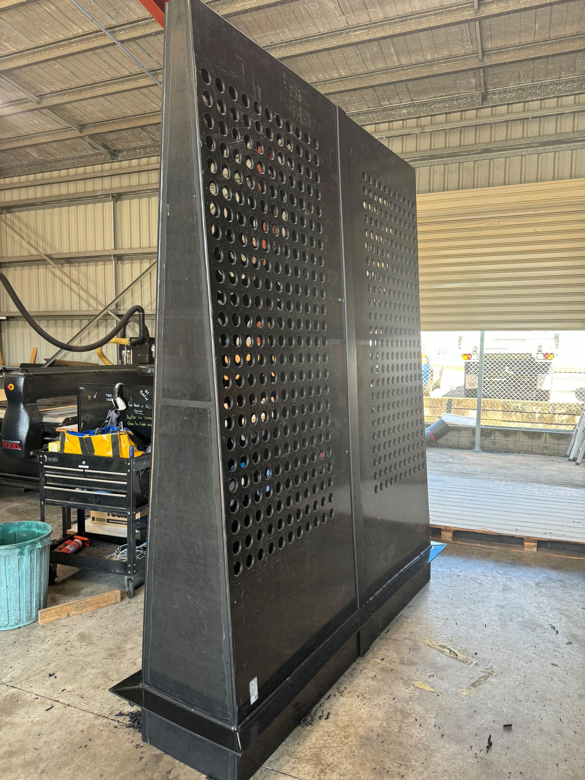 Tall black metal perforated panel standing in a workshop with shelves and tools in the background — Advanced Poly in Darwin, NT — Advanced Poly in Darwin, NT 