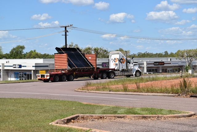 Flatbed truck hauling a black metal ramp on a suburban roadside under a blue sky — Advanced Poly in Darwin, NT — Advanced Poly in Darwin, NT 
