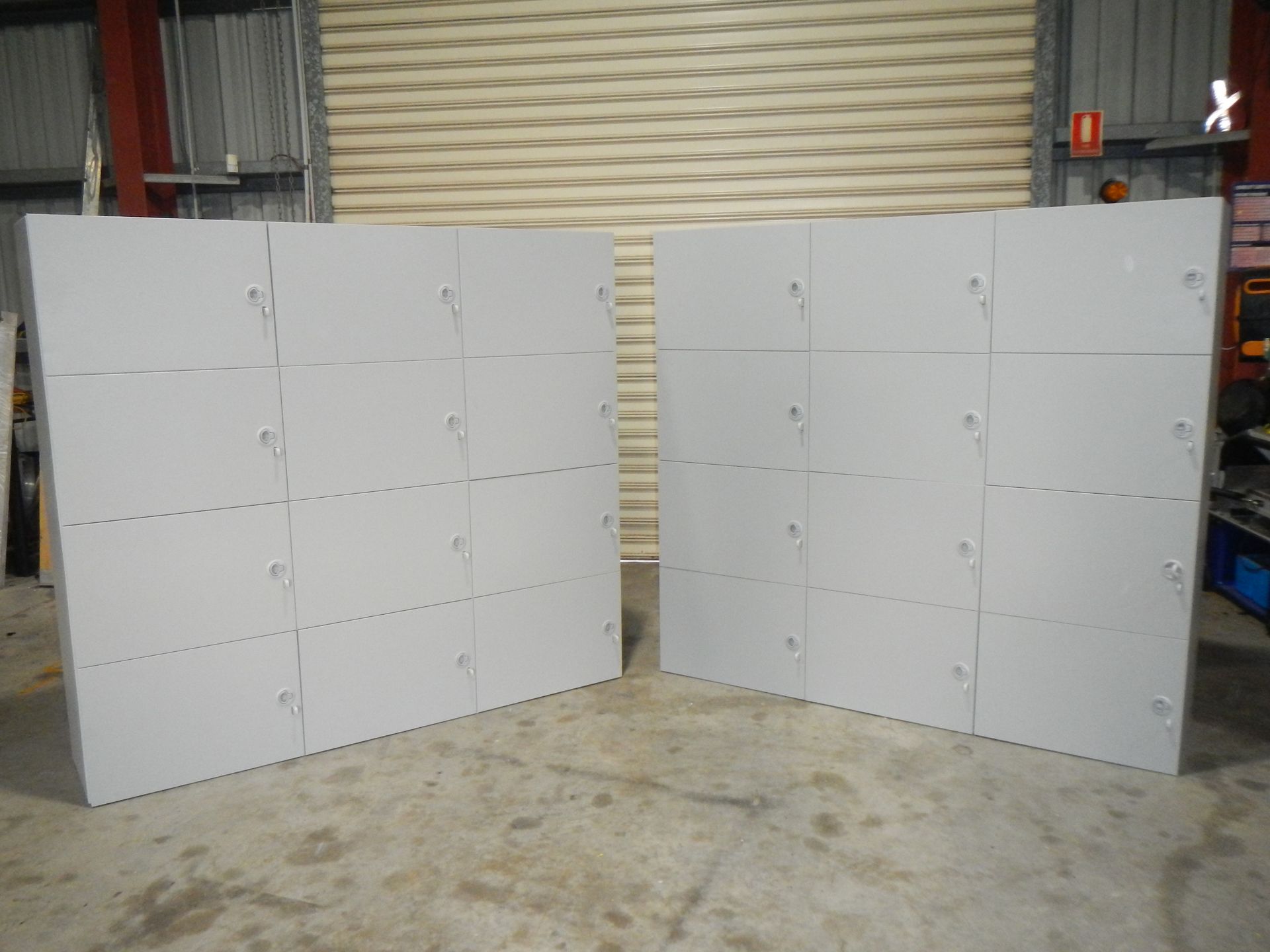 Two large white modular wall panels standing in an industrial garage with a closed roll-up door. — Advanced Poly in Darwin, NT