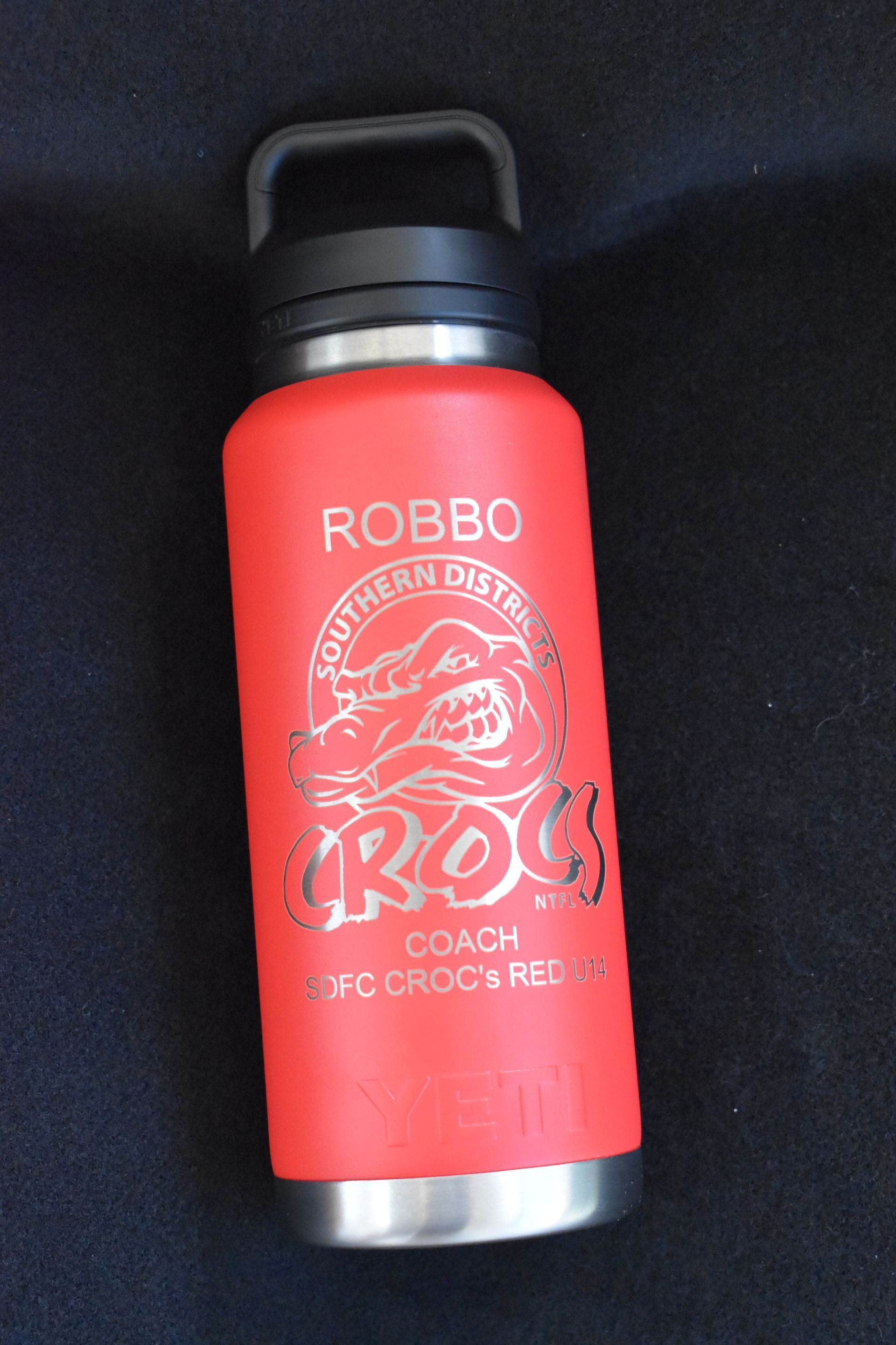 Red ROBBO insulated bottle with a logo, lying on a dark fabric background. — Advanced Poly in Darwin, NT 