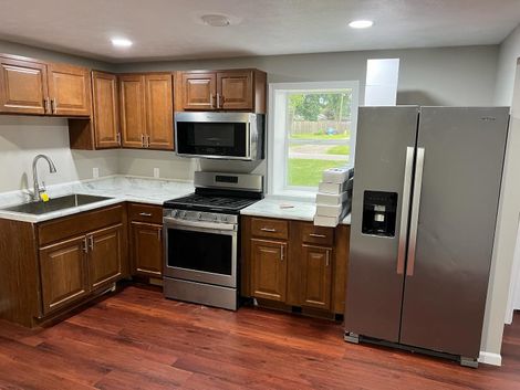 Kitchen with wooden cabinets, stainless steel appliances, and marble countertops.
