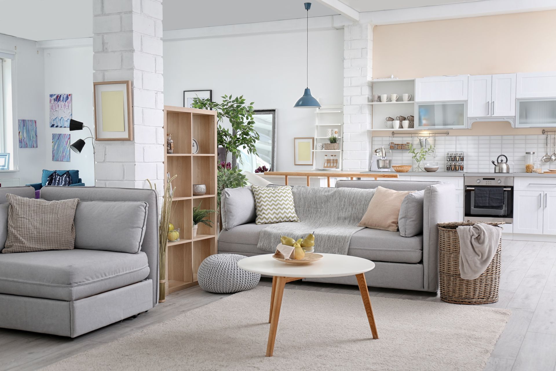 Living room and kitchen combo with a gray sofa, white walls, and a small table.