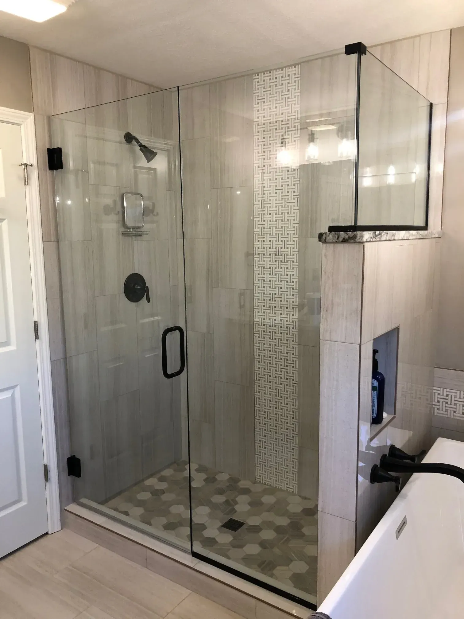 Glass walk-in shower with chrome fixtures, pebble floor, and white tile bathroom walls