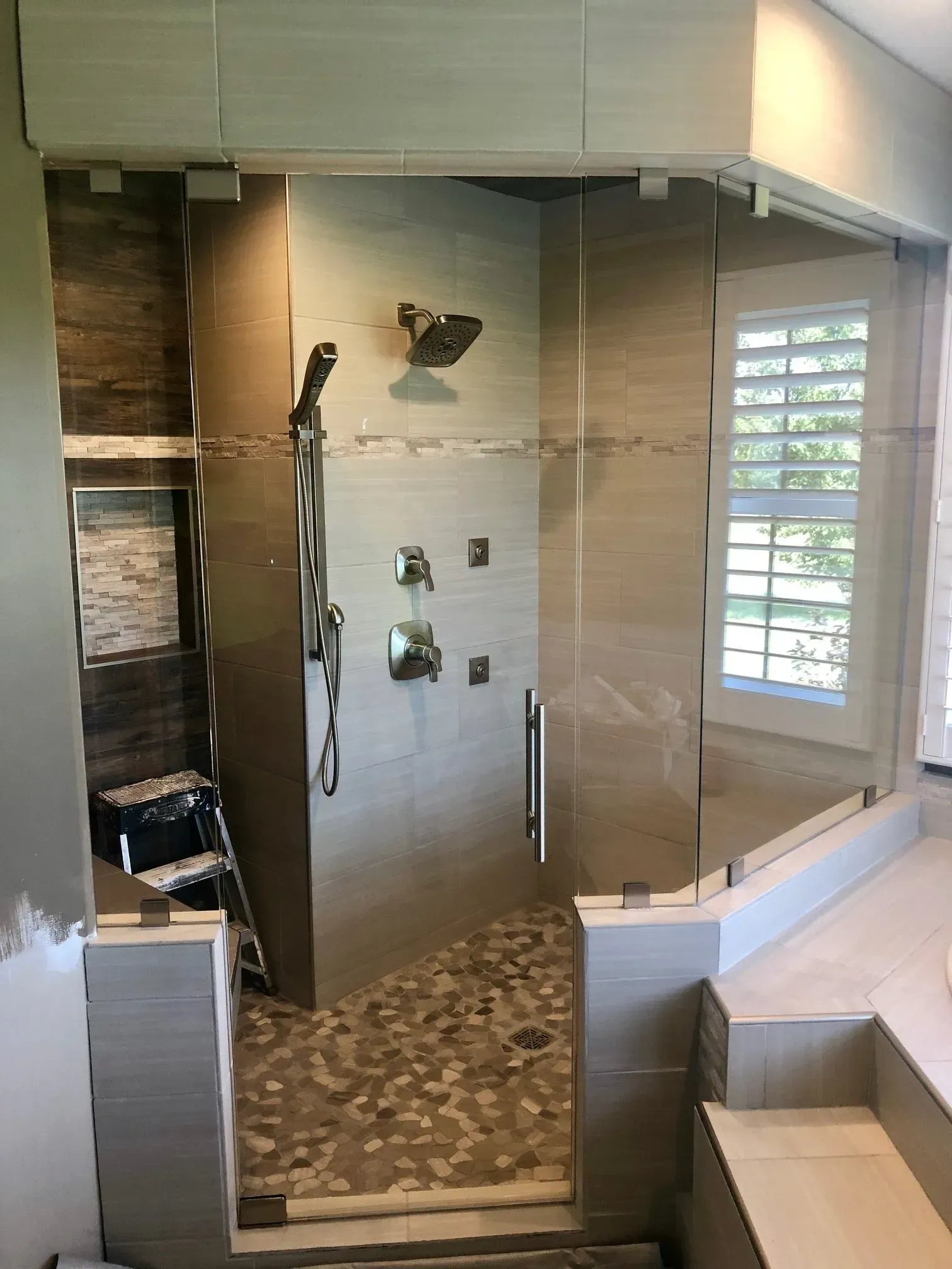 Modern bathroom with tiled walk-in shower, glass enclosure, and built-in bench near a window