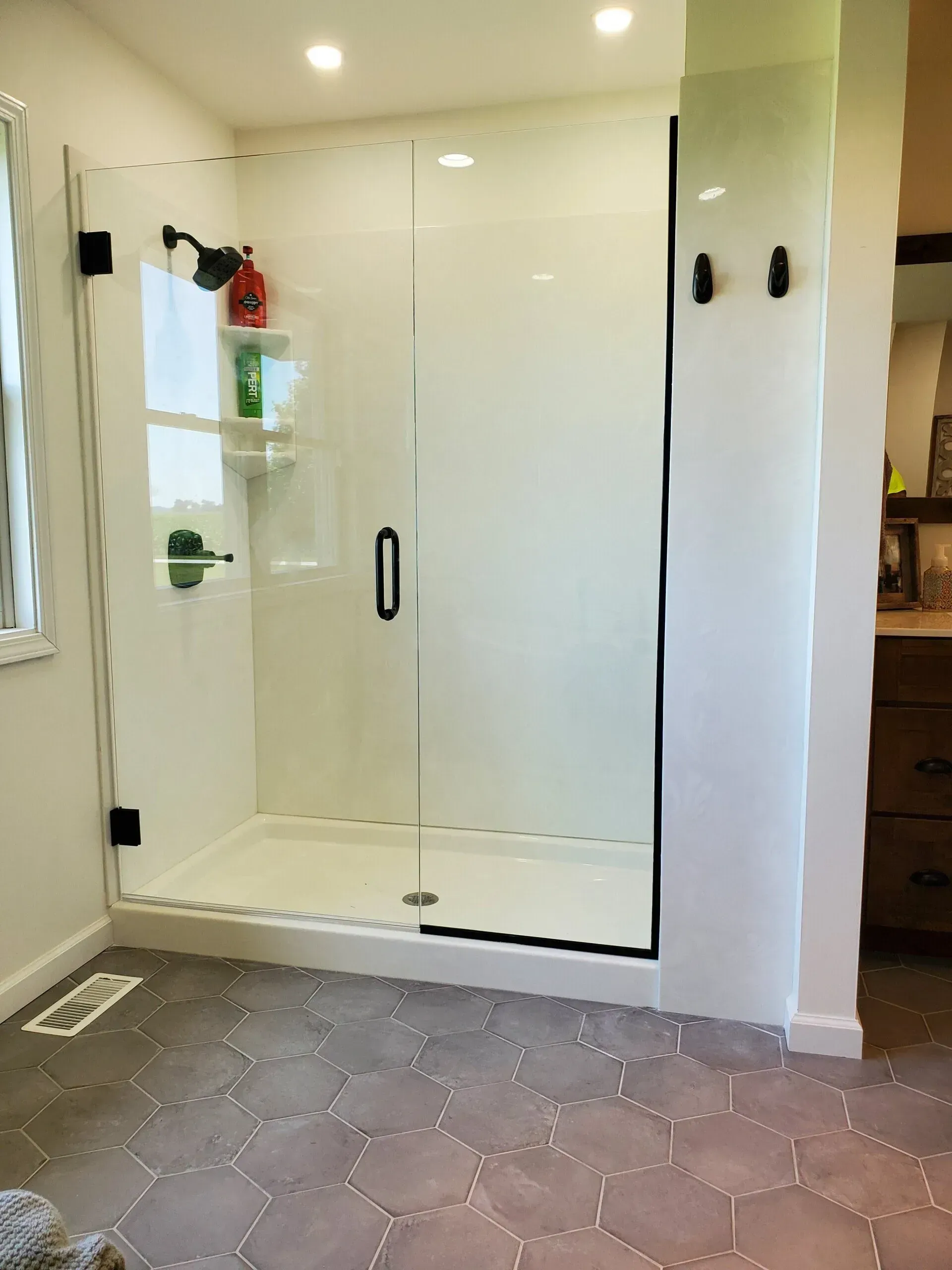 Modern white walk-in shower with glass door in a tiled bathroom