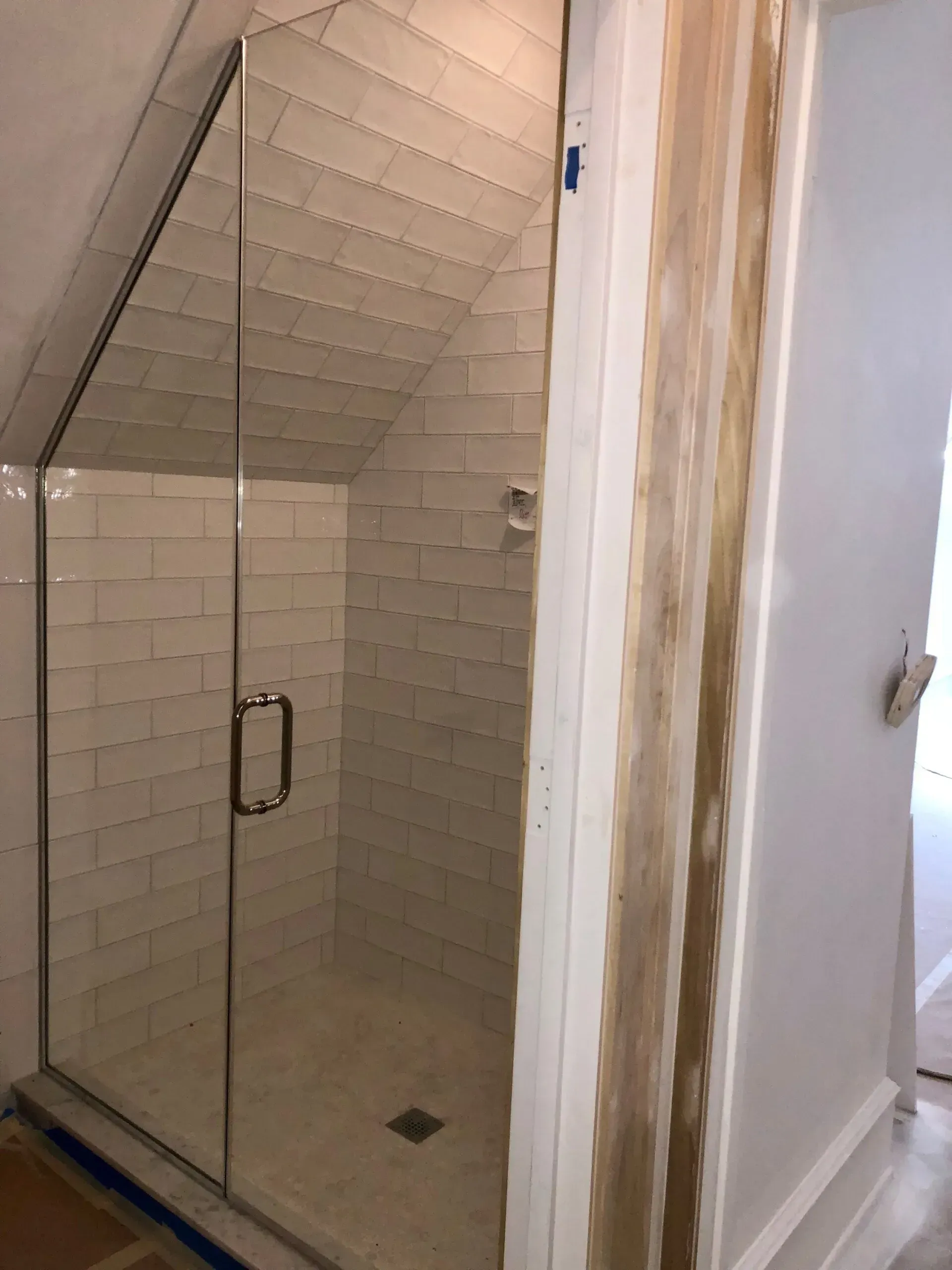 Glass shower stall with tiled walls and a sloped ceiling in a bathroom