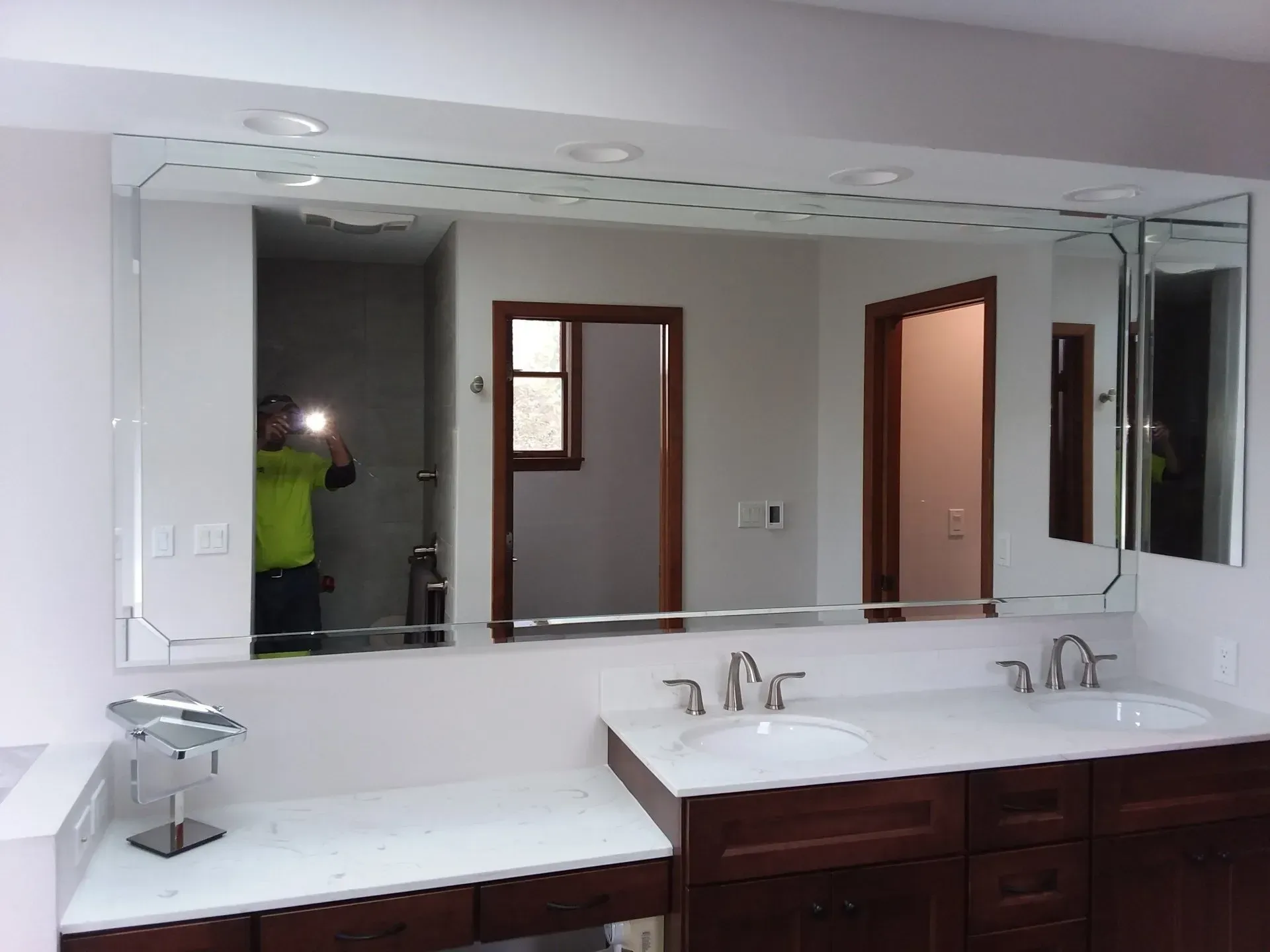Modern bathroom vanity with double sinks, large mirror, and brown cabinets, viewed from the side.