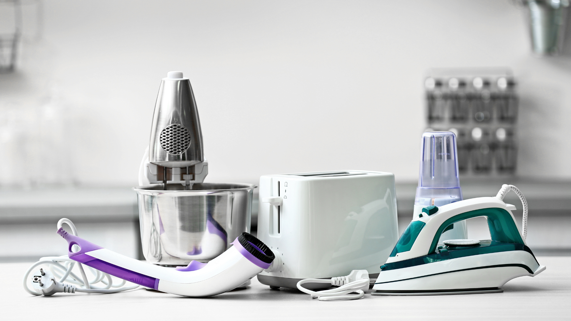 Various small kitchen appliances: mixer, toaster, iron, blender, and lint remover.