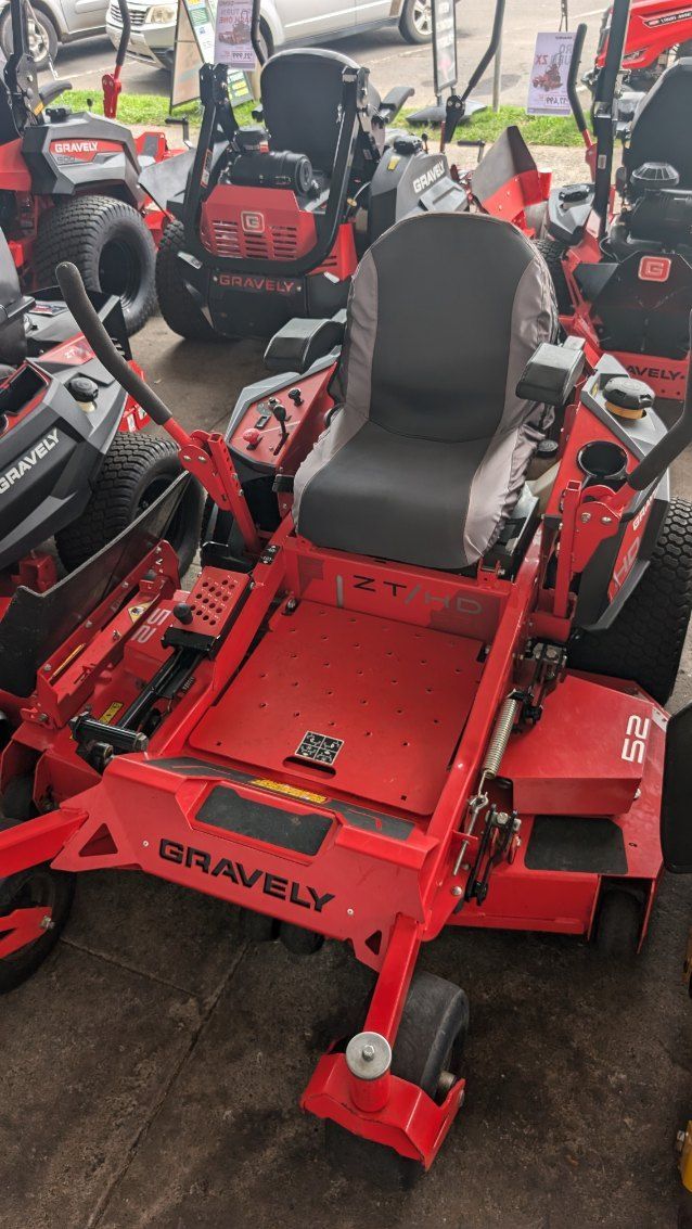 A Red Lawn Mower is Parked Next to a Row of Other Lawn Mowers — FarmCare In Mullumbimby, NSW