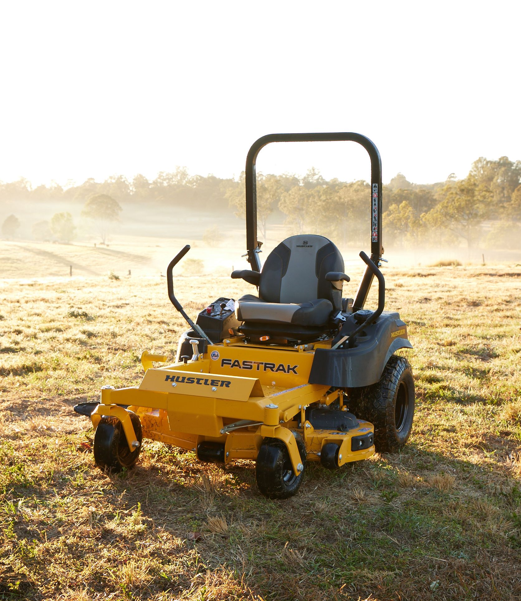 hustler ride on mower in front of asunset