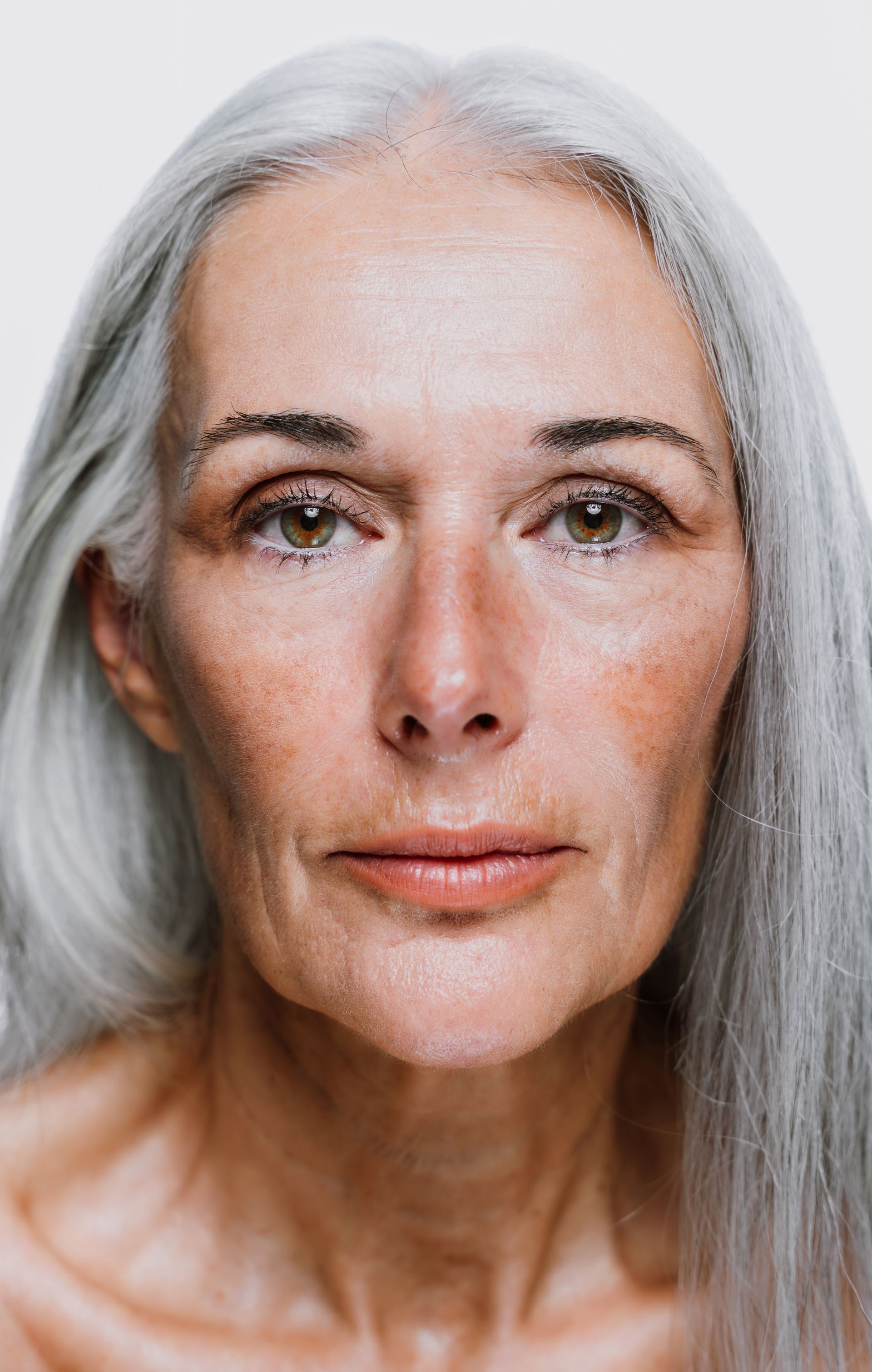 A close up of a woman 's face with long gray hair.