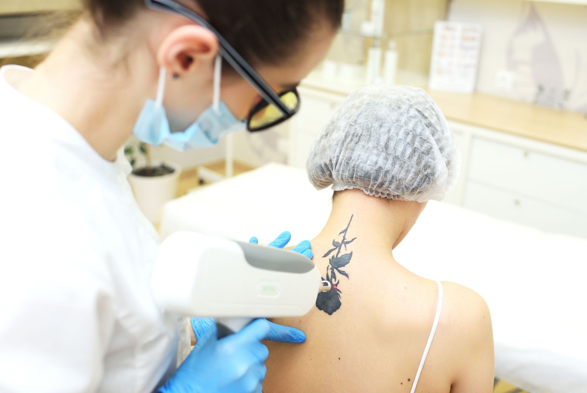 A woman is getting a tattoo removed from her back.
