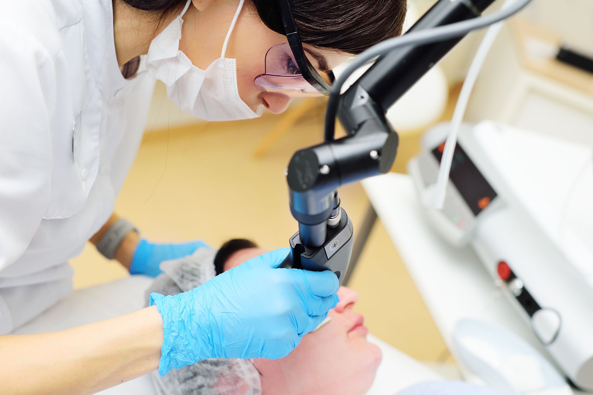 A woman is getting a laser treatment on her face.