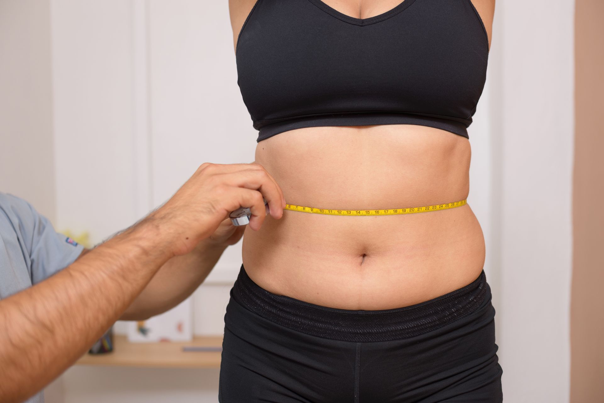 A man is measuring a woman 's waist with a tape measure.