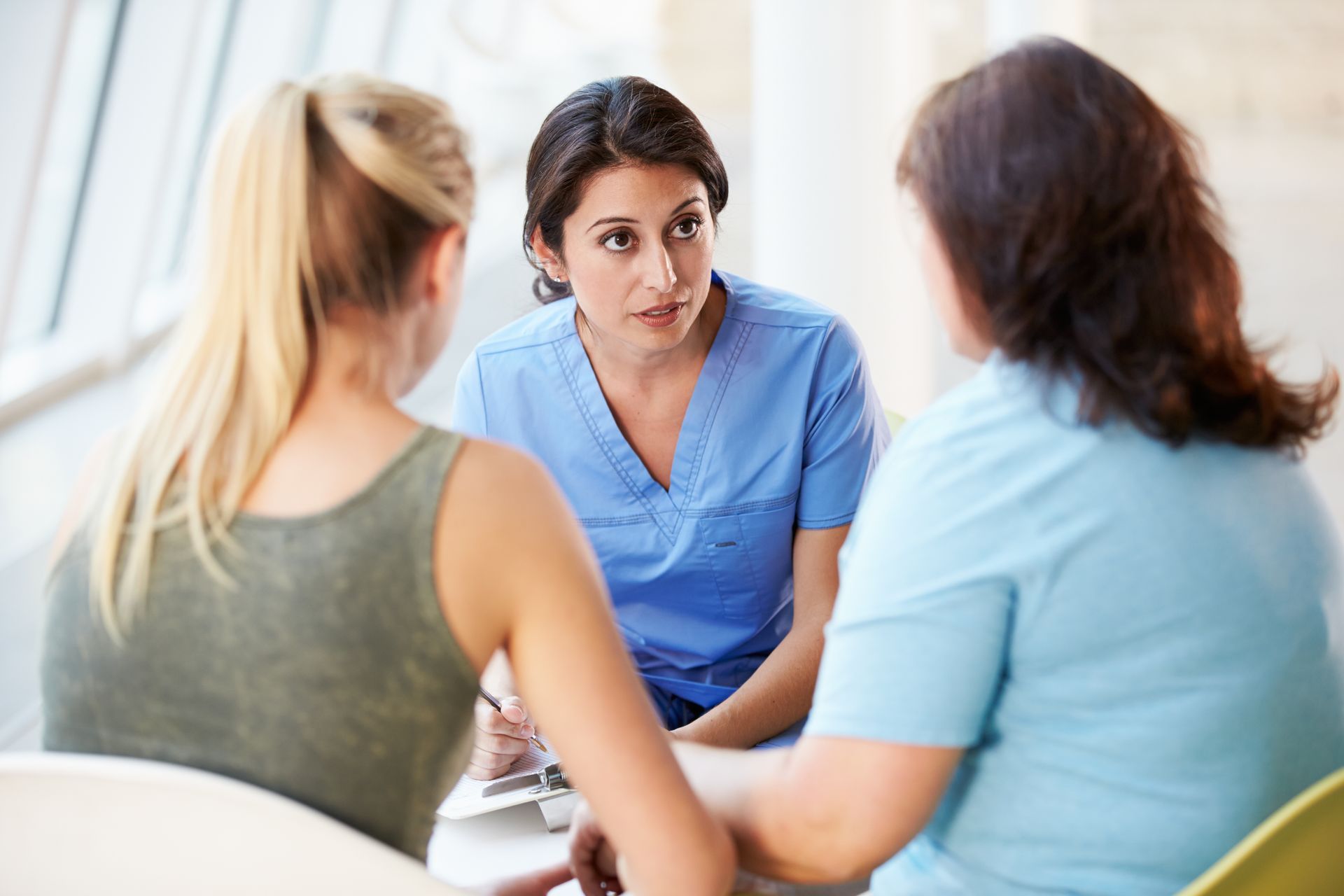 A nurse is talking to two women at a table.