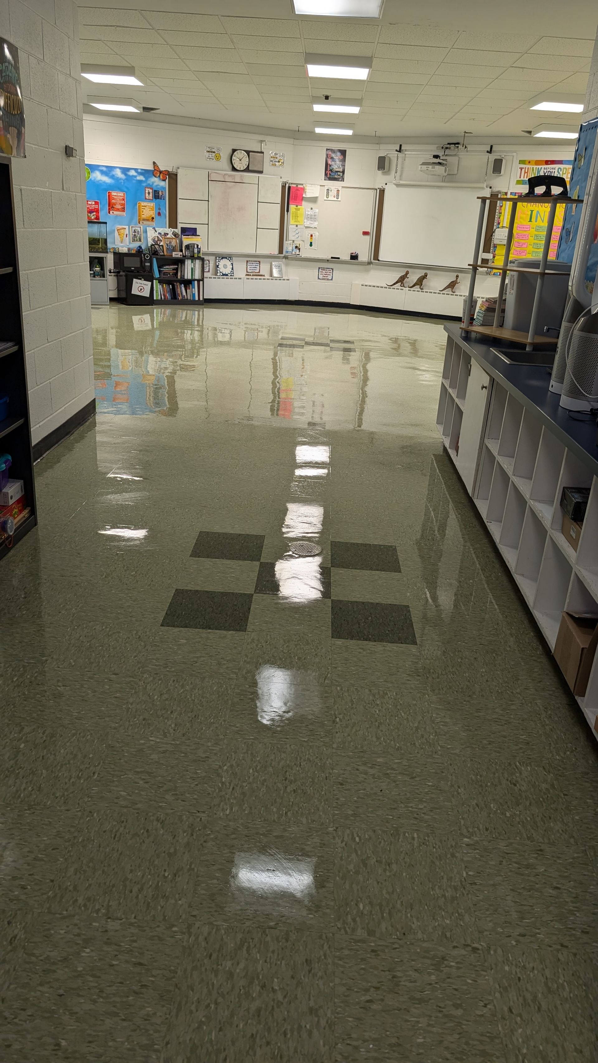 Empty store aisle with glossy tile floor, shelves on both sides, and bright ceiling lights reflecting on the floor
