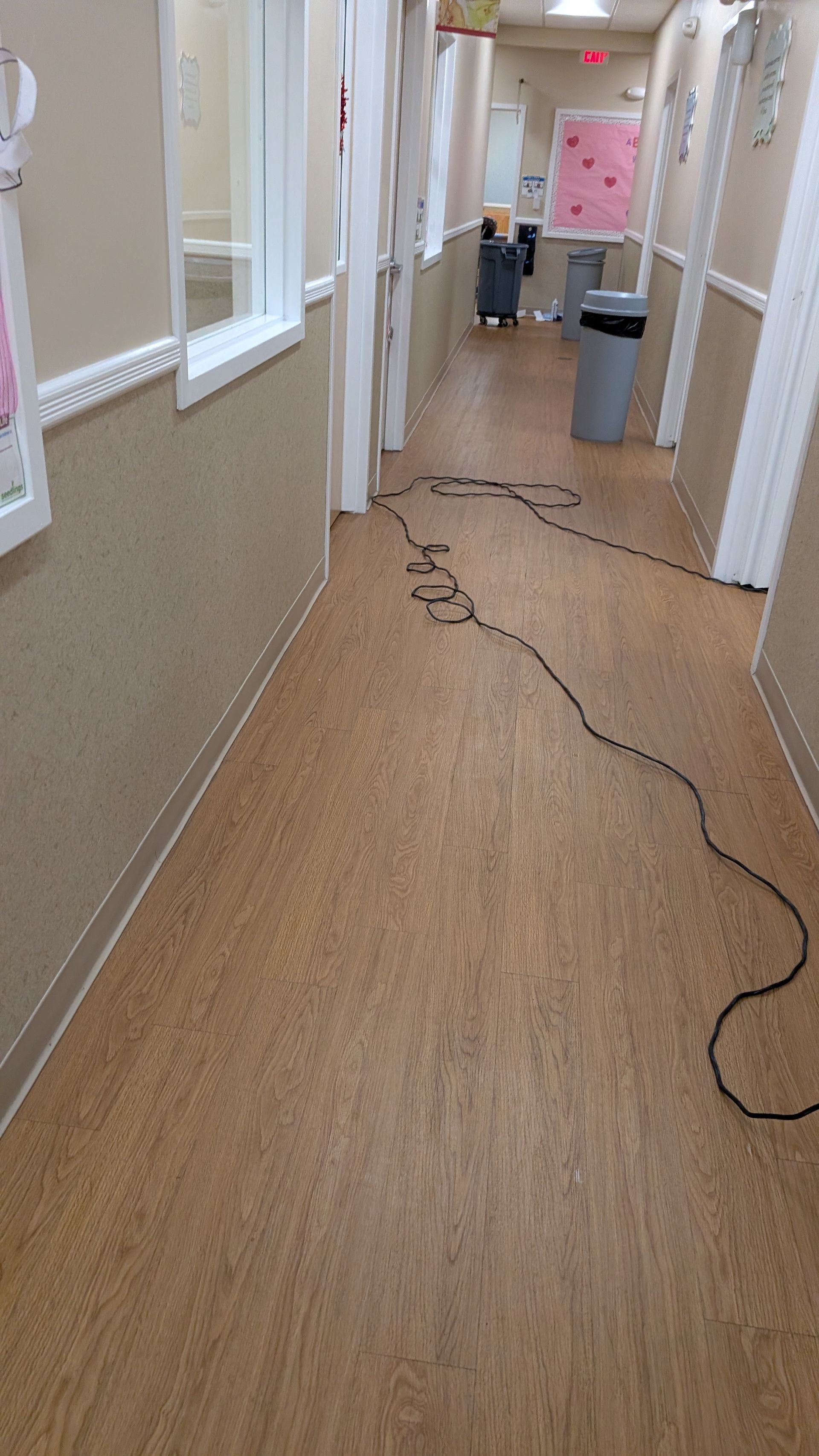 Hallway with a long black cable stretched across the floor toward a person near the end.