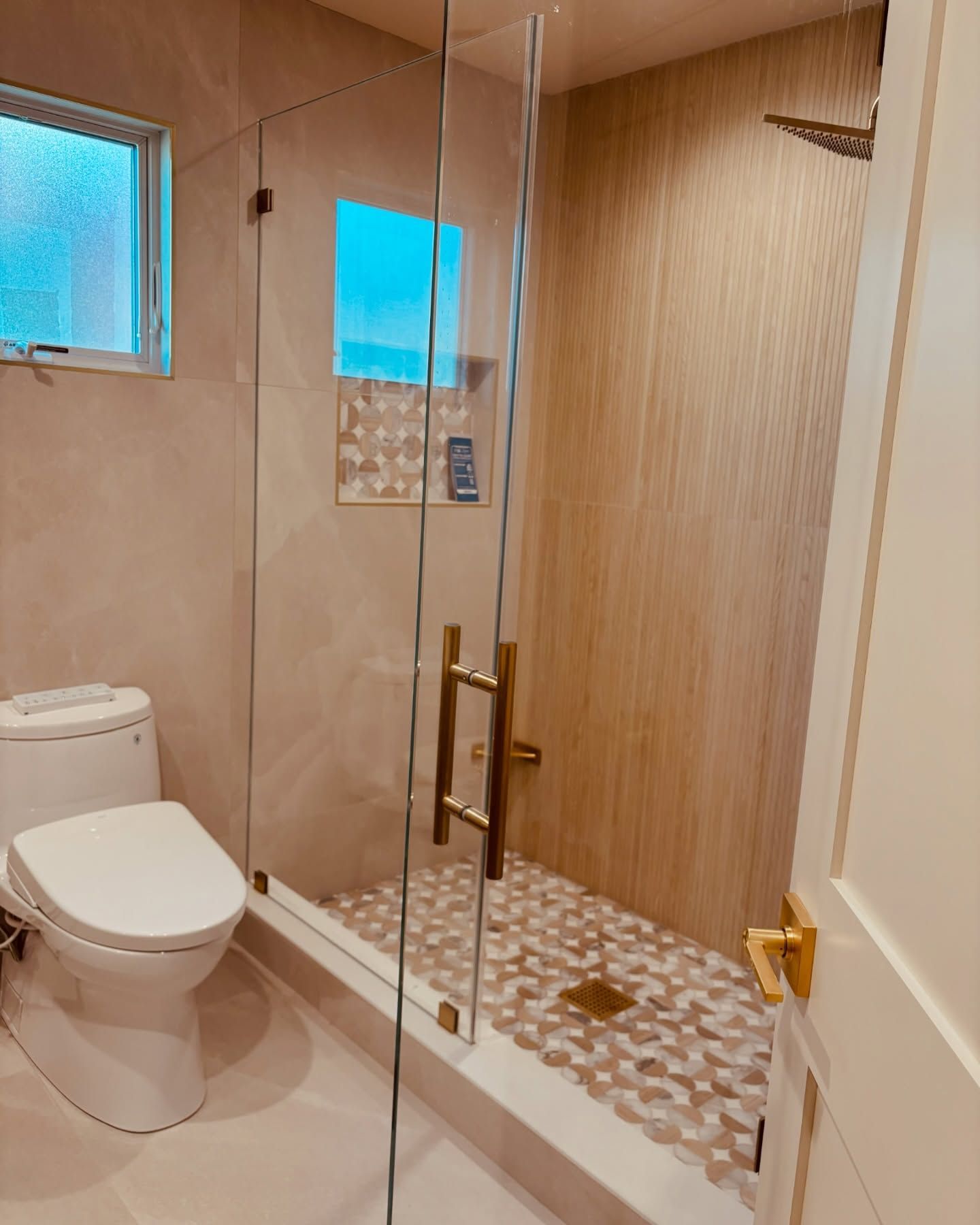 Modern bathroom with toilet, glass shower enclosure, and wood-paneled shower area