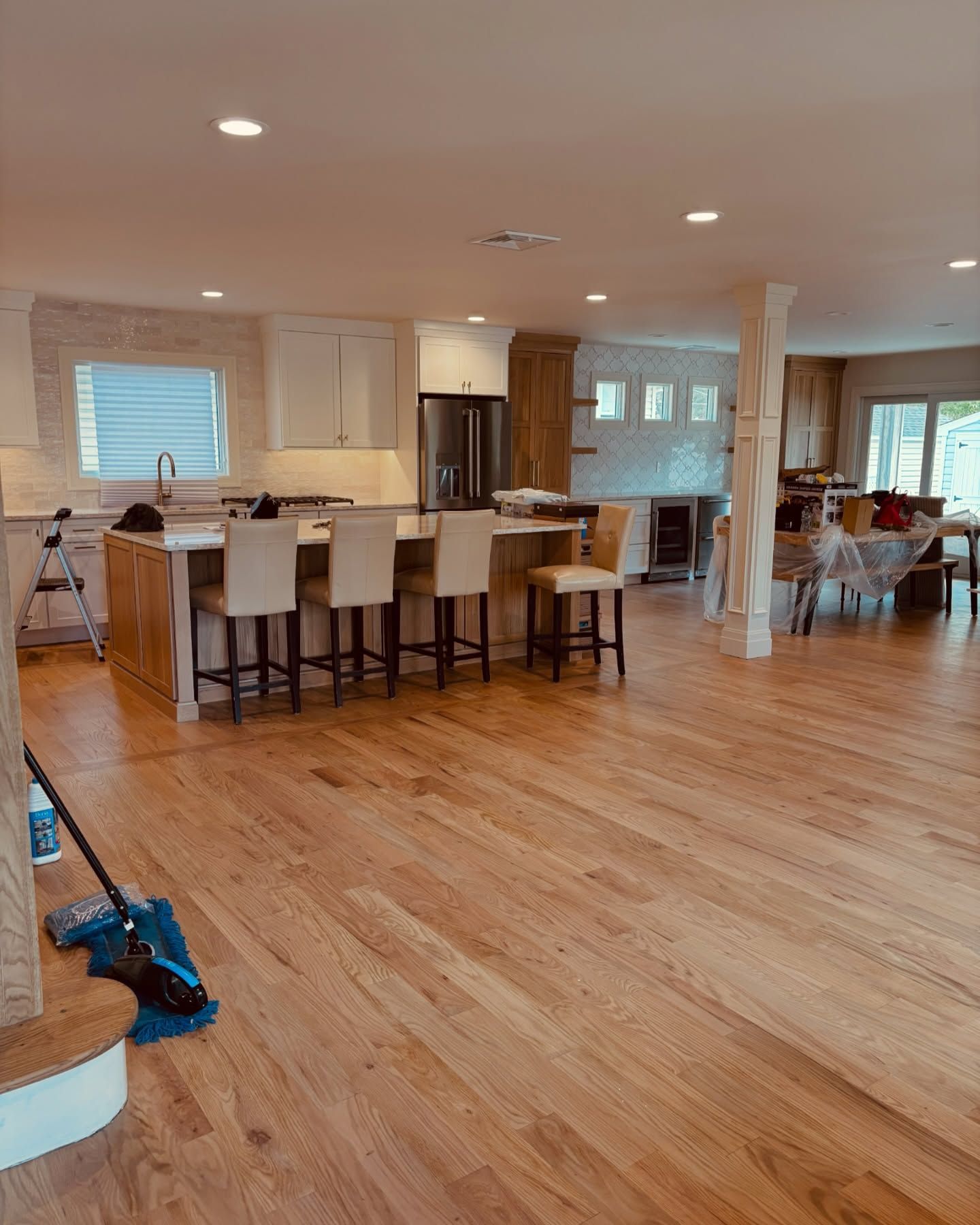 Bright modern kitchen with white cabinets, stainless appliances, and a wooden island with wicker bar stools