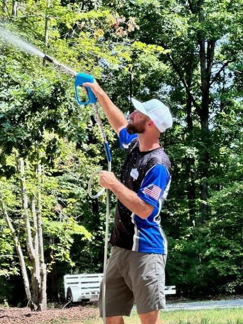 A man is using a hose to spray water on a tree.