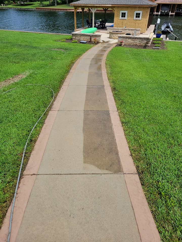A concrete walkway leading to a house next to a lake.