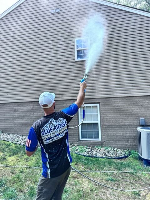A man is spraying water on the side of a house.