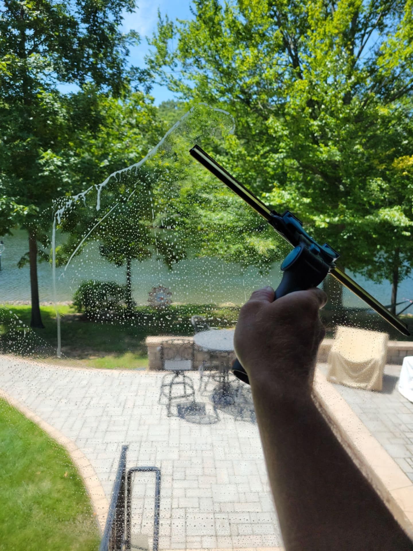 A person is cleaning a window with a high pressure washer.