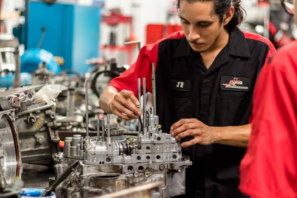 A man is working on a car engine in a factory.