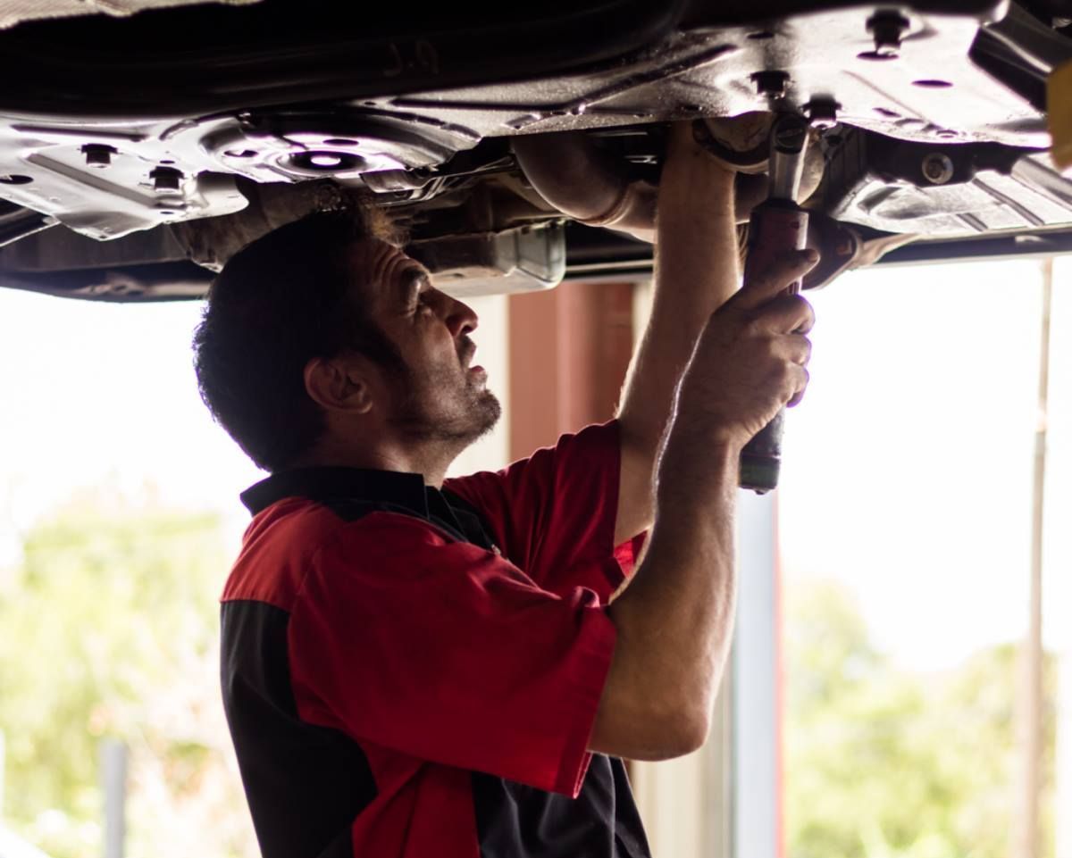 A man is working under a car with a wrench.