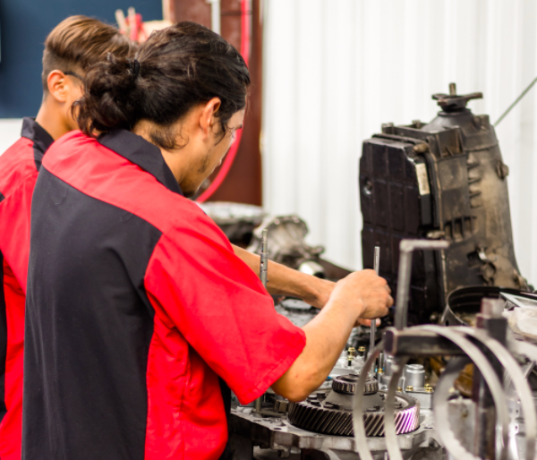 Two men are working on a machine in a garage.