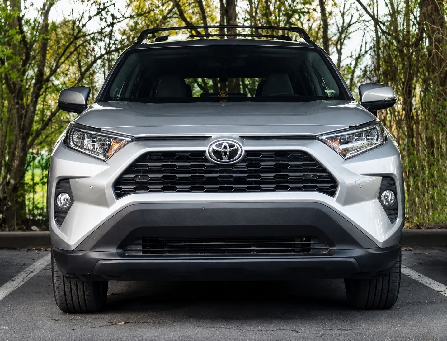 Front view of a silver Toyota SUV parked on a road with trees in the background
