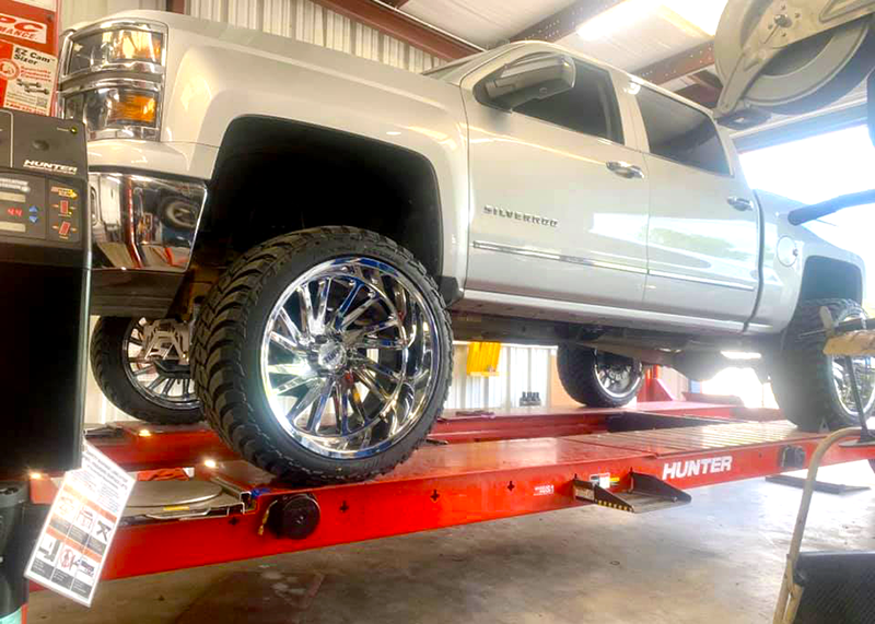 A silver truck is sitting on top of a red lift in a garage.