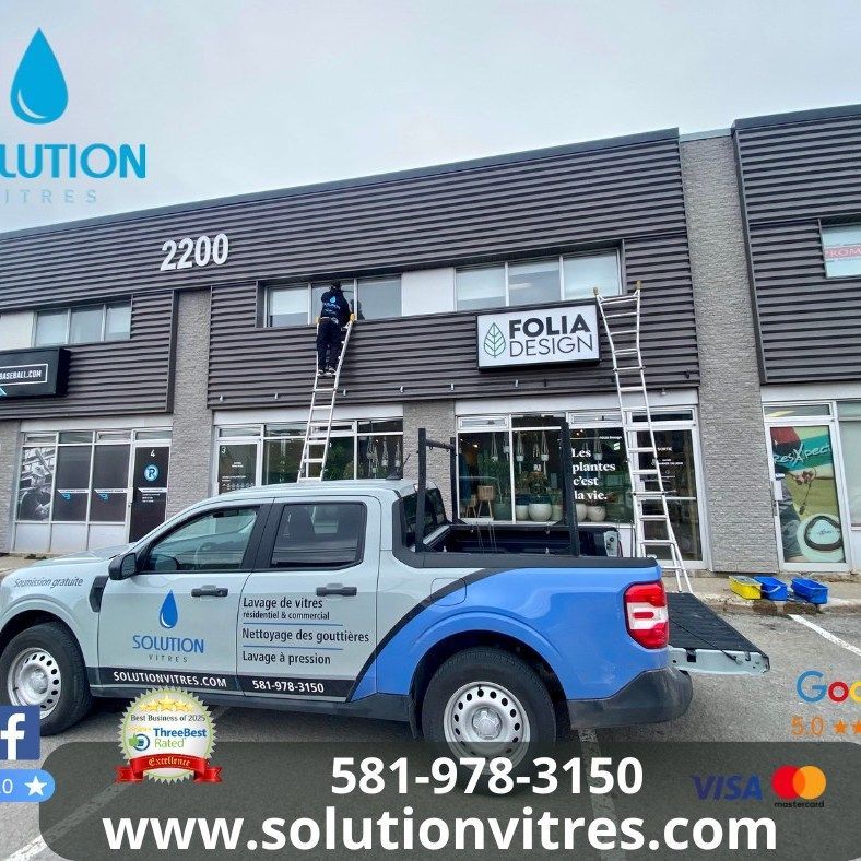 Camion utilitaire stationné devant la boutique Folla Design, avec un employé sur une échelle et le logo bleu de la marque Solution.